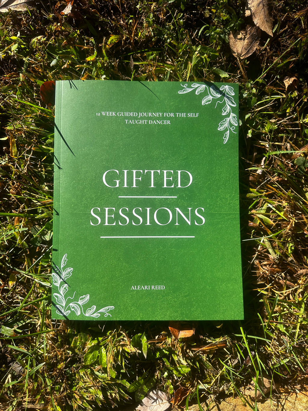 Green book titled 'Gifted Sessions' on grass